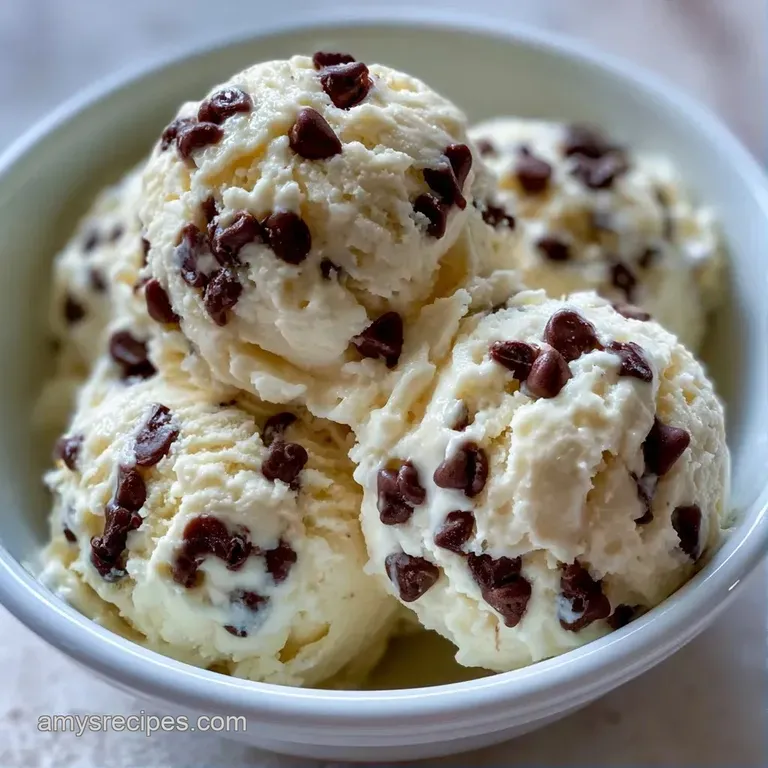Three neat spheres of pale frozen cream in a chilled glass bowl, garnished with a fresh mint leaf and a cherry.