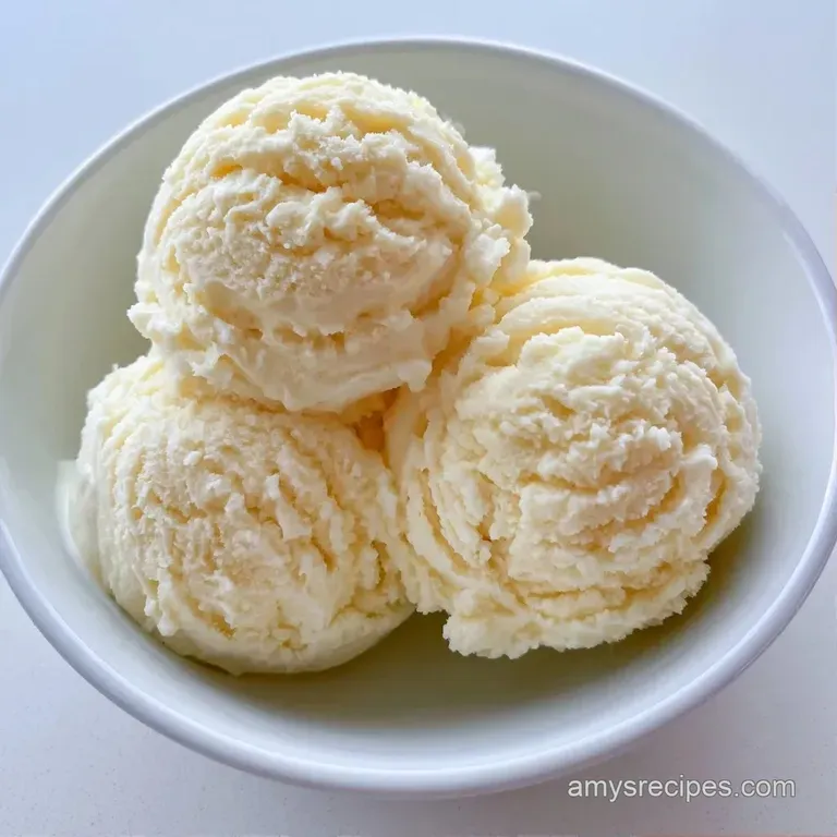 Pristine scoops of ivory-colored frozen cream in a chilled glass dish, accented by a fresh sprig of green mint.